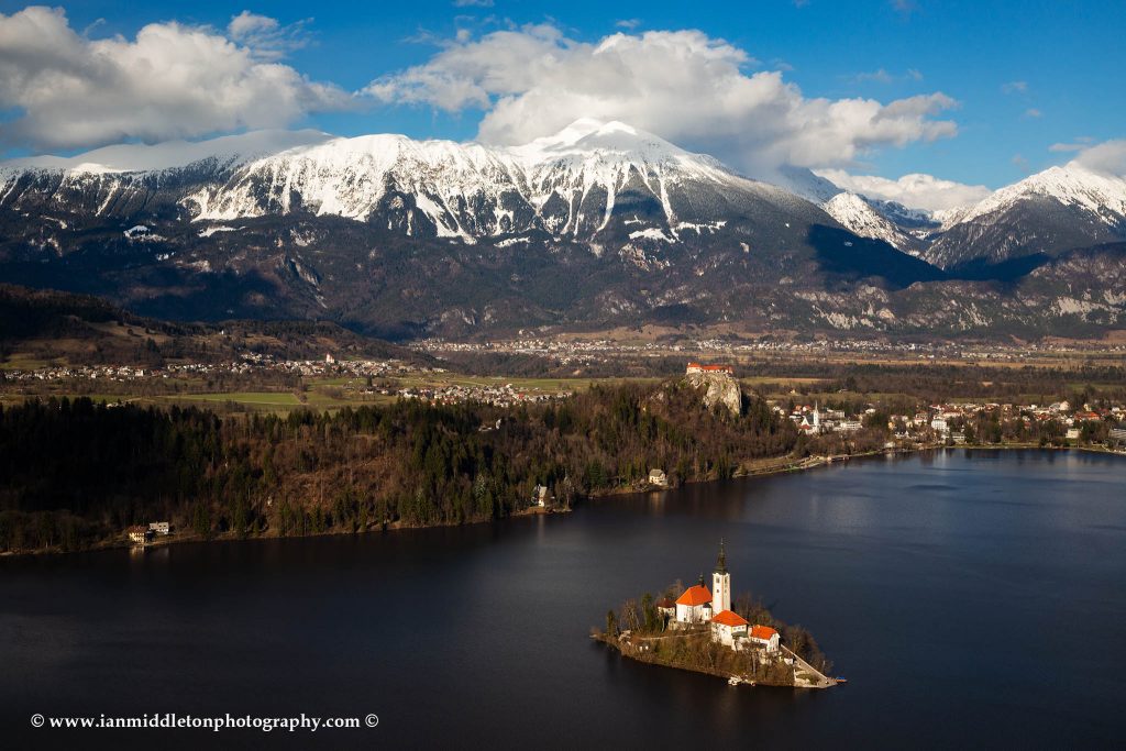 View across Lake Bled to the island church and clifftop castle from Mala Osojnica in spring, Slovenia.